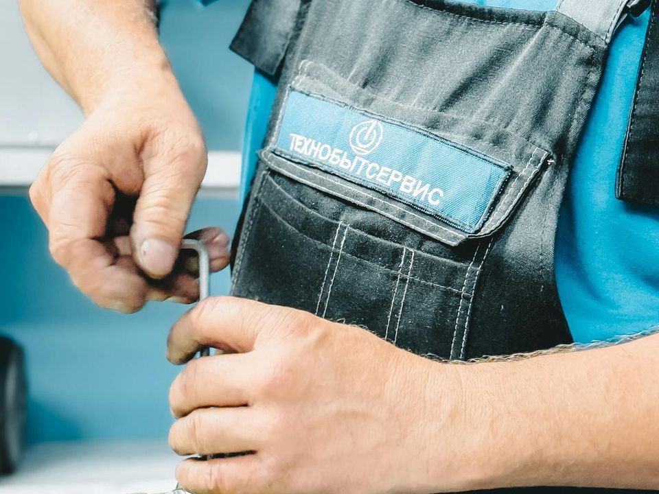 Plumber in work overalls repairing a pipe with a wrench
