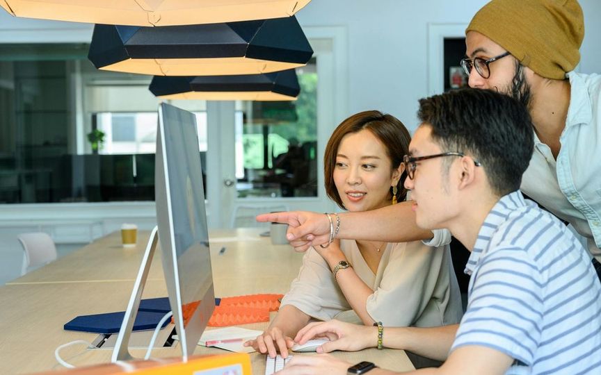 Team reviewing a website project on a desktop monitor