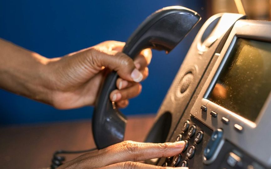 Person dialing a desk phone in a business office